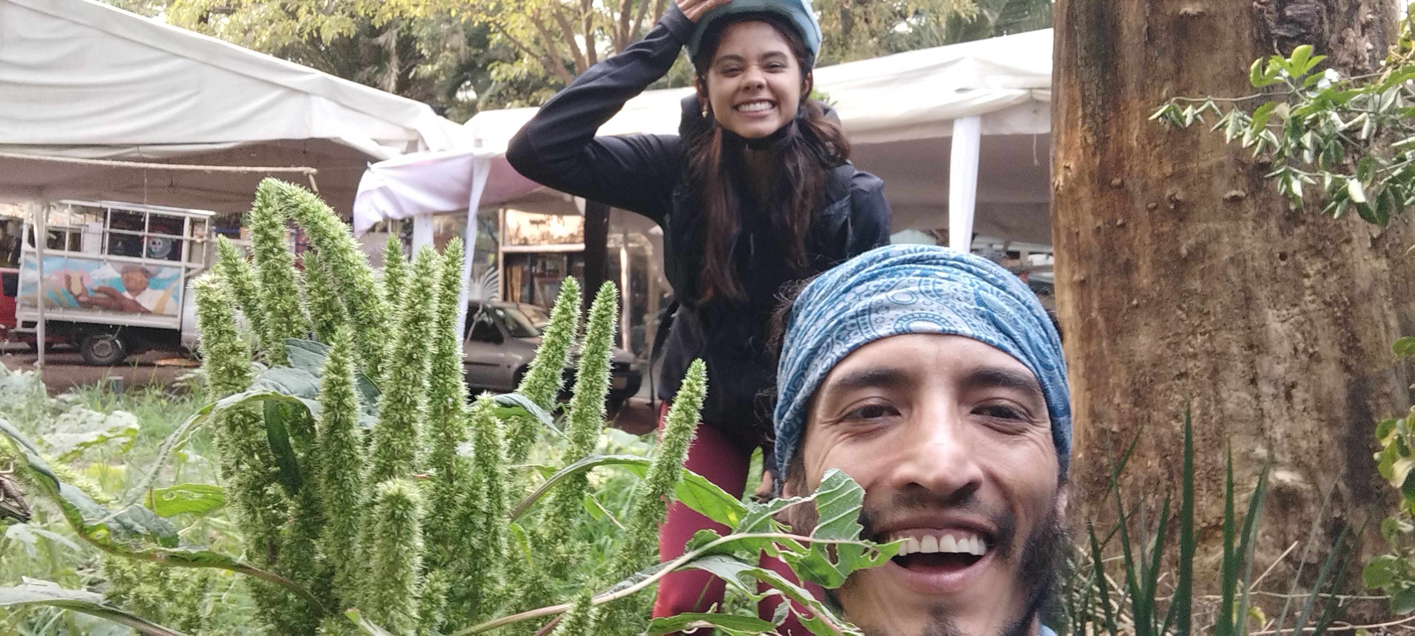 Amarantonio y un compañero sonriendo entre plantas de amaranto en un evento.